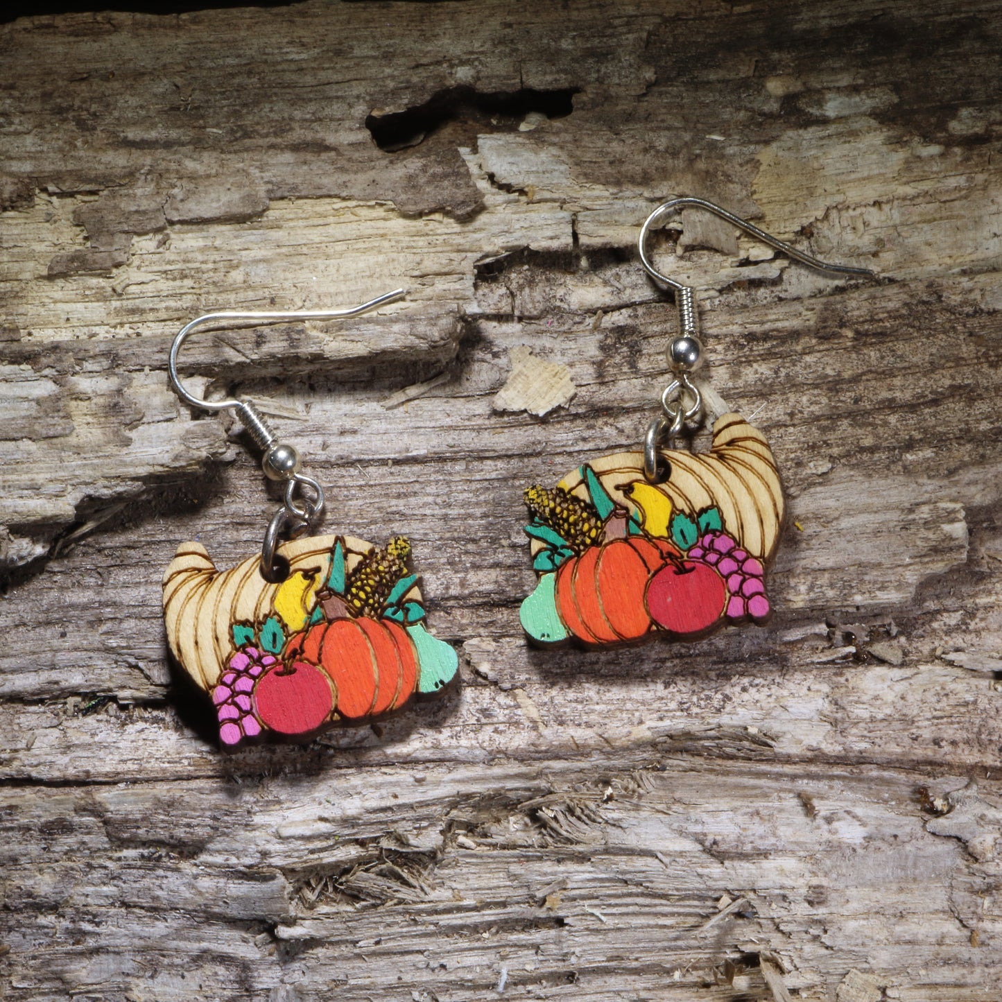 Cornucopia wooden dangle earrings featuring a hand-painted horn of plenty filled with colorful autumn fruits and vegetables. Lightweight Thanksgiving harvest earrings with hypoallergenic .925 sterling silver hooks, perfect for fall outfits, Thanksgiving celebrations, harvest festivals, autumn lovers, and seasonal jewelry gifts.