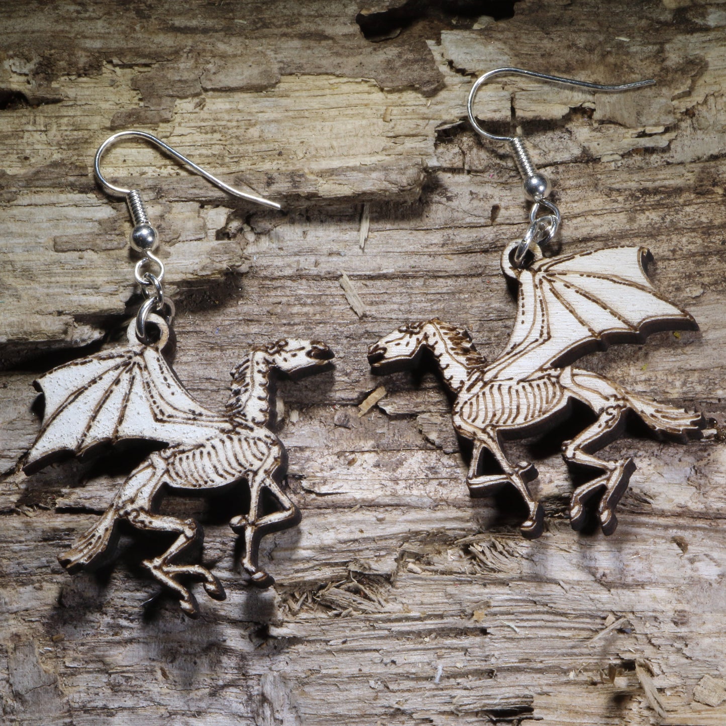 Hand-painted skeletal winged horse wooden dangle earrings featuring a striking fantasy design with gothic flair. Lightweight statement earrings perfect for Pegasus lovers, dark fantasy fans, mythology enthusiasts, and unique gothic jewelry collectors.
