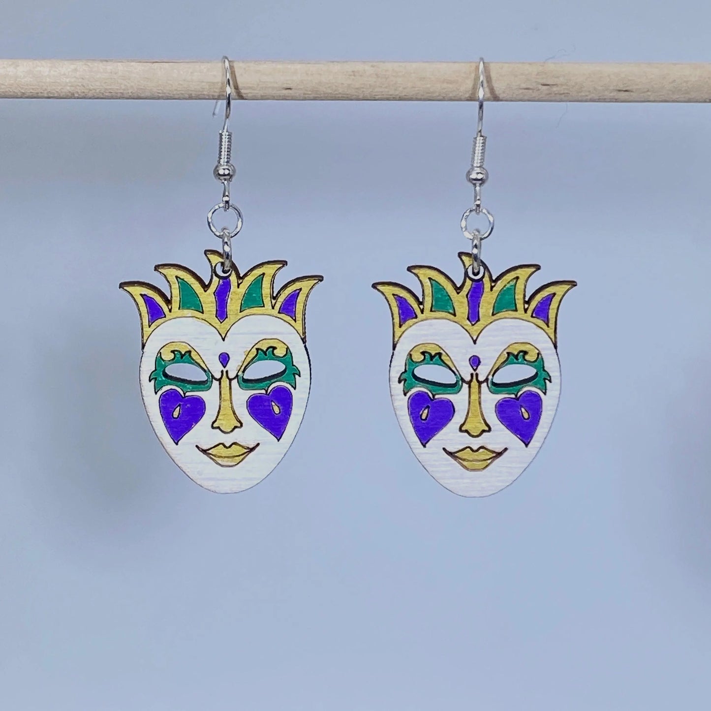 Handcrafted Mardi Gras mask wooden dangle earrings featuring a festive masquerade mask in traditional purple, green, gold, and white colors. Lightweight laser-cut wooden earrings with hypoallergenic .925 sterling silver hooks, perfect for Mardi Gras celebrations, New Orleans festivals, carnival parties, masquerade costumes, Louisiana gifts, and handmade festival jewelry.