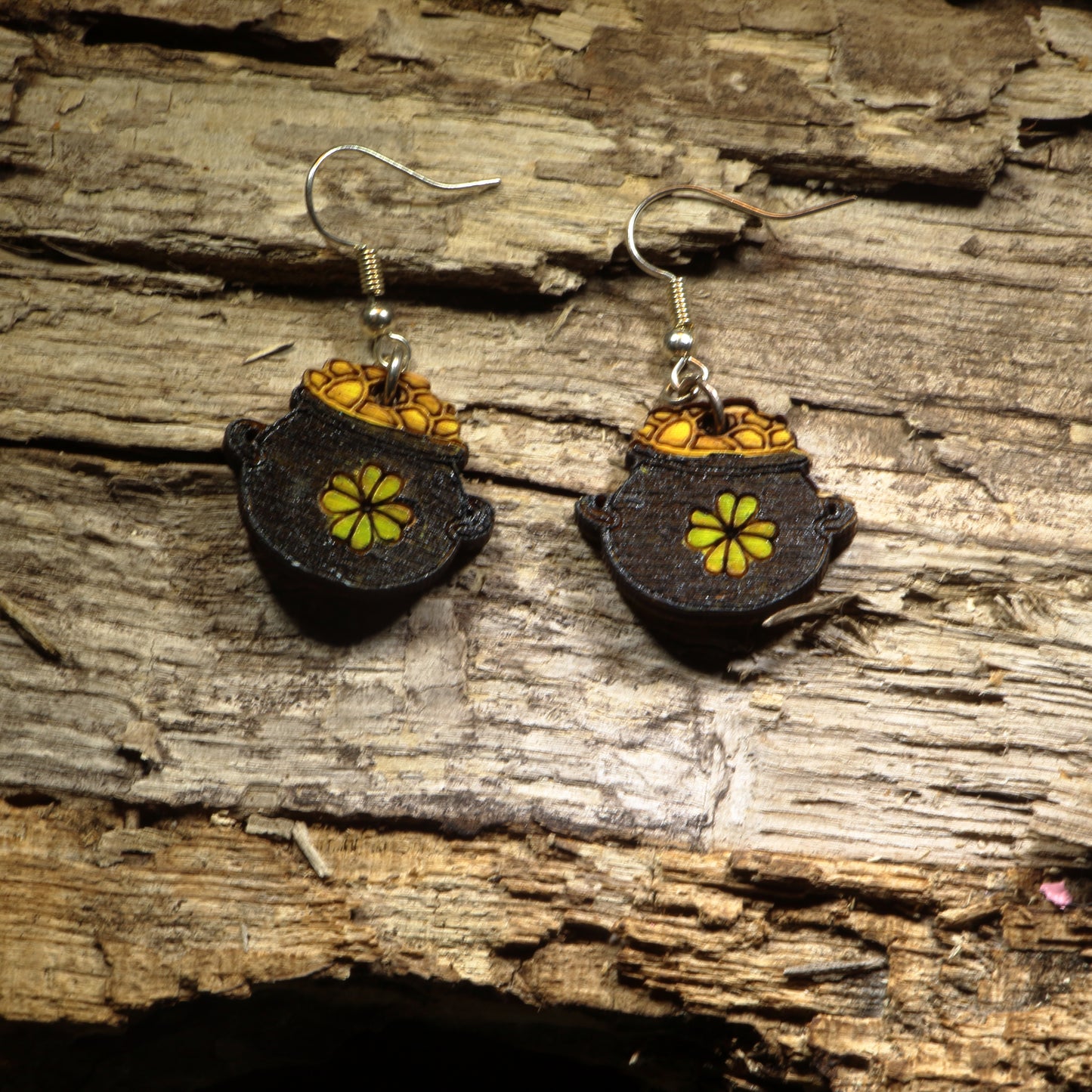 Hand-painted wooden pot of gold dangle earrings featuring a treasure-filled pot overflowing with bright gold coins inspired by Irish folklore. Crafted from lightweight wood with hypoallergenic .925 sterling silver hooks, these festive earrings are perfect for St. Patrick's Day celebrations, Irish heritage, lucky charm enthusiasts, leprechaun lovers, Celtic festivals, and anyone who enjoys whimsical Irish-inspired jewelry.