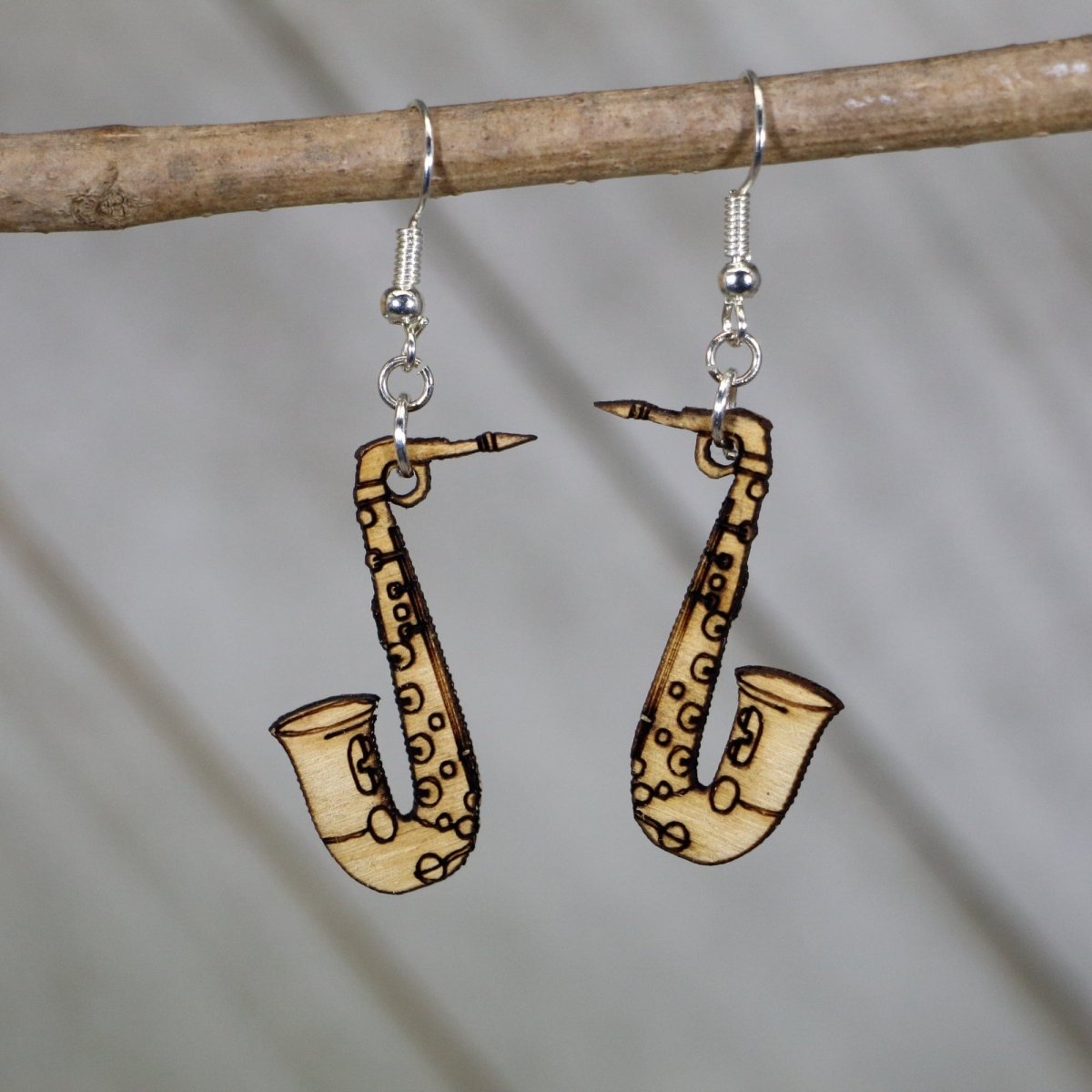 Hand-painted wooden saxophone dangle earrings featuring a detailed curved instrument with engraved keys and flared bell and hypoallergenic sterling silver hooks, lightweight jewelry for jazz lovers and band musicians by Cate’s Concepts