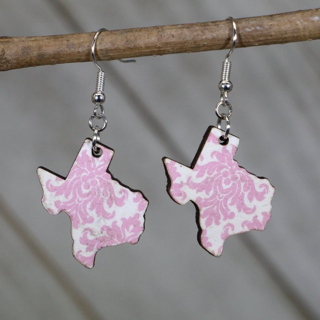 Hand-painted wooden Texas floral dangle earrings featuring a pink state-shaped design with blooming flower accents and hypoallergenic sterling silver hooks, lightweight jewelry for Texas lovers and state pride enthusiasts by Cate’s Concepts