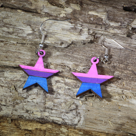 Hand-painted wooden bisexual pride star dangle earrings featuring pink, purple, and blue bisexual flag stripes, hypoallergenic sterling silver hooks, and lightweight LGBTQ+ pride jewelry for bisexual pride celebrations and queer accessory lovers by Cate's Concepts.