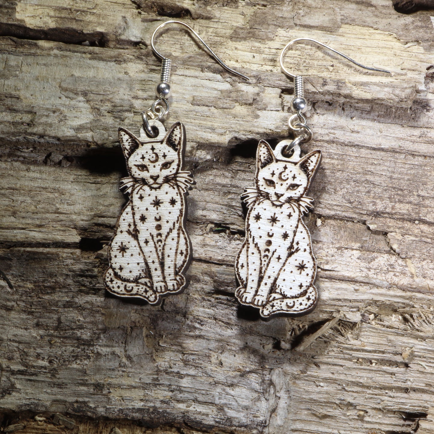 Handcrafted celestial cat wooden dangle earrings featuring an elegant cat silhouette adorned with moon phases, stars, and celestial details. Lightweight laser-cut wooden earrings with hypoallergenic .925 sterling silver hooks, perfect for cat lovers, witchy fashion, celestial jewelry collectors, moon enthusiasts, gothic style, and mystical handmade accessories.