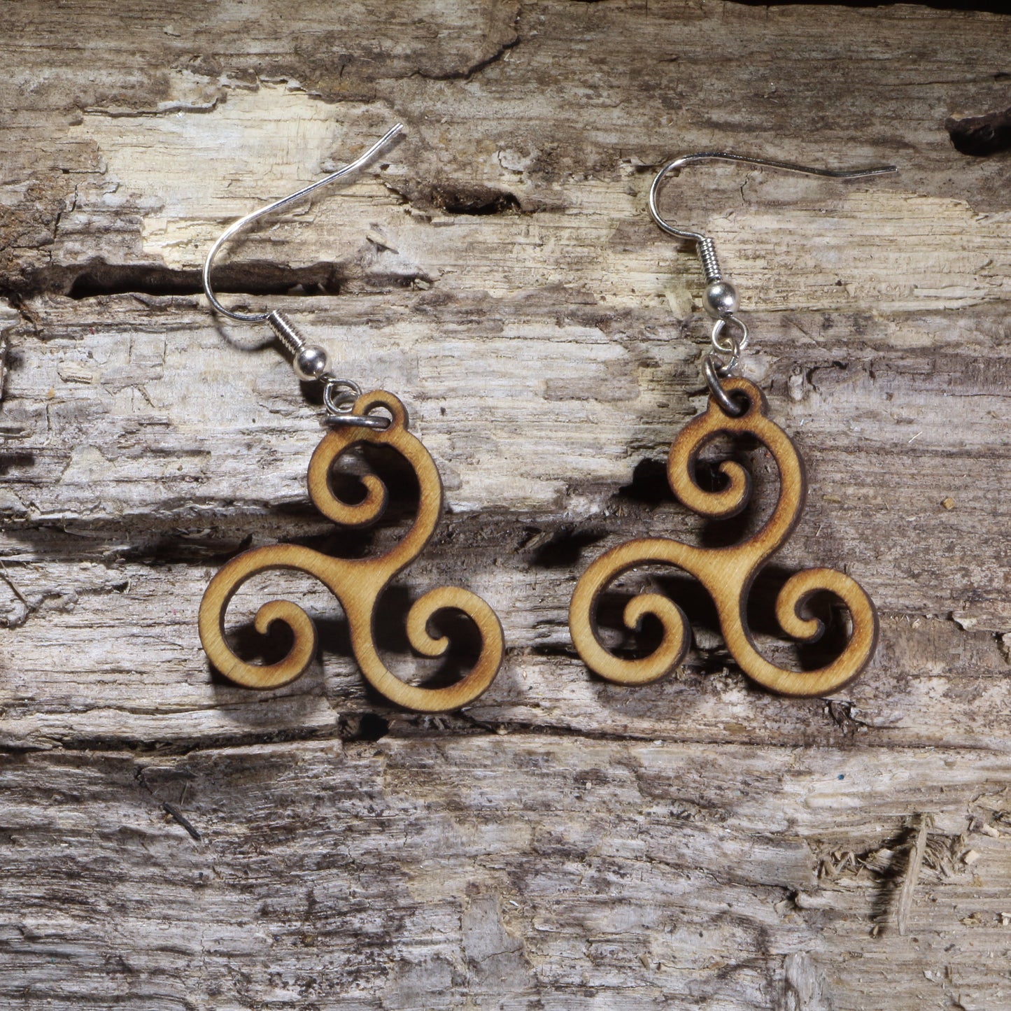 Handcrafted Celtic Triskele wooden dangle earrings featuring the traditional triple spiral symbol representing unity, balance, and eternity. Lightweight laser-cut wooden earrings with hypoallergenic .925 sterling silver hooks, perfect for Celtic heritage, Irish culture, pagan traditions, spiritual jewelry lovers, and timeless handcrafted accessories.