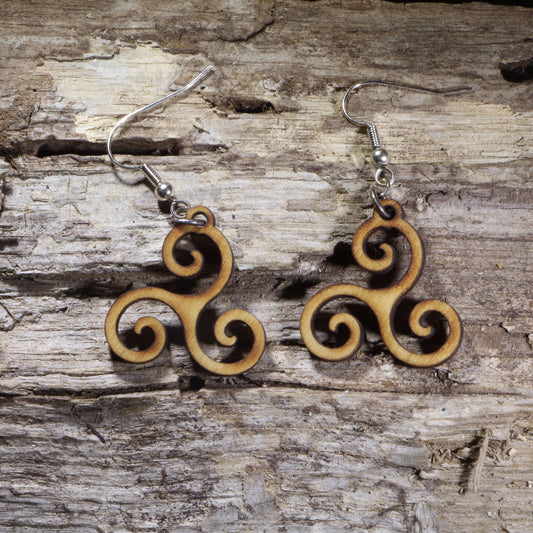 Handcrafted Celtic Triskele wooden dangle earrings featuring the traditional triple spiral symbol representing unity, balance, and eternity. Lightweight laser-cut wooden earrings with hypoallergenic .925 sterling silver hooks, perfect for Celtic heritage, Irish culture, pagan traditions, spiritual jewelry lovers, and timeless handcrafted accessories.