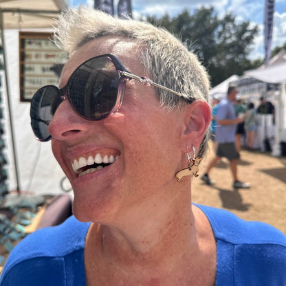 Customer wearing handmade wooden Dachshund dangle earrings with hypoallergenic .925 sterling silver hooks at an outdoor artisan market. Lightweight wiener dog earrings shown in real-life wear, perfect for Dachshund lovers and unique pet jewelry fans.