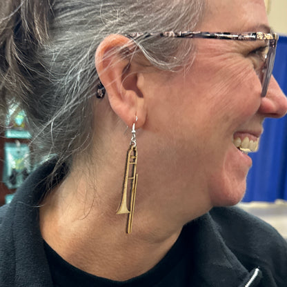 Customer wearing handmade wooden trombone dangle earrings with hypoallergenic .925 sterling silver hooks. Lightweight music-themed earrings shown in everyday wear, ideal for trombone players, marching band members, music educators, and concert band gifts.