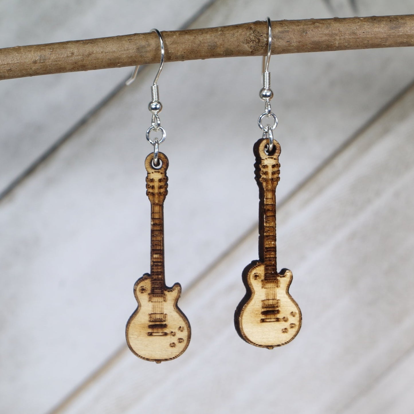 Hand-painted wooden electric guitar dangle earrings featuring a detailed guitar body with strings and pickups and hypoallergenic sterling silver hooks, lightweight jewelry for rock musicians and music lovers