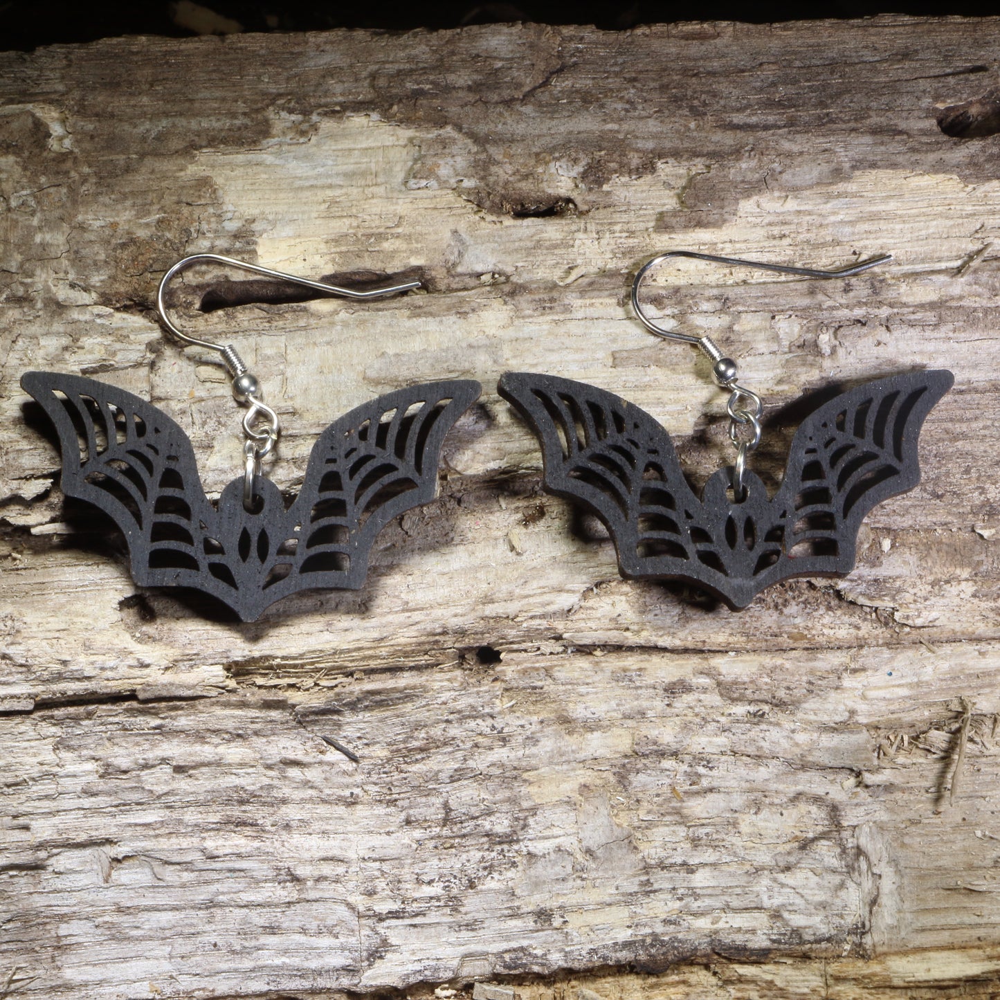 Handcrafted gothic bat wooden dangle earrings featuring detailed flying bat silhouettes with engraved wing accents. Lightweight laser-cut wooden earrings with hypoallergenic .925 sterling silver hooks, perfect for Halloween lovers, gothic fashion, bat enthusiasts, spooky season, vampire fans, and alternative style jewelry.