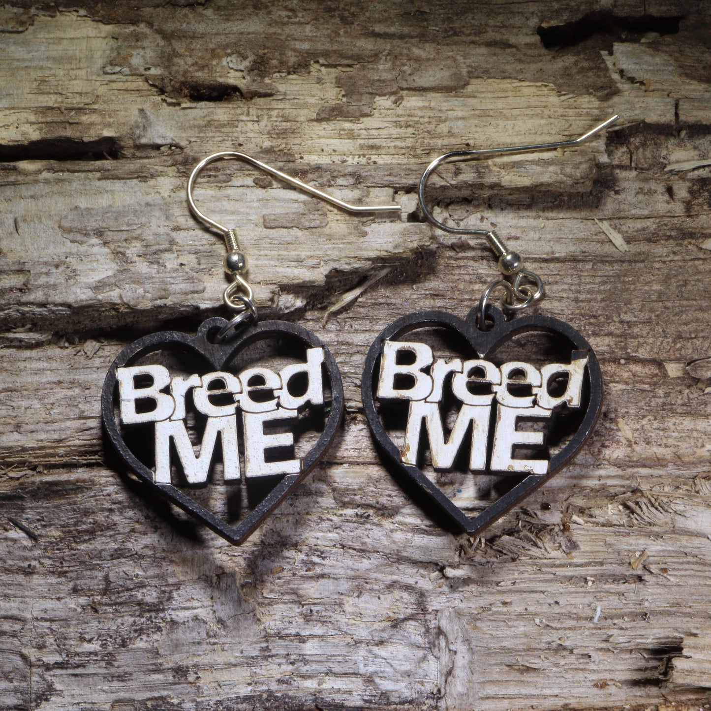 Hand-painted “Breed Me” heart wooden dangle earrings featuring bold black-and-white lettering for a cheeky adult statement. Lightweight novelty earrings perfect for risqué humor, bachelorette parties, alternative style, and funny conversation-starting jewelry.