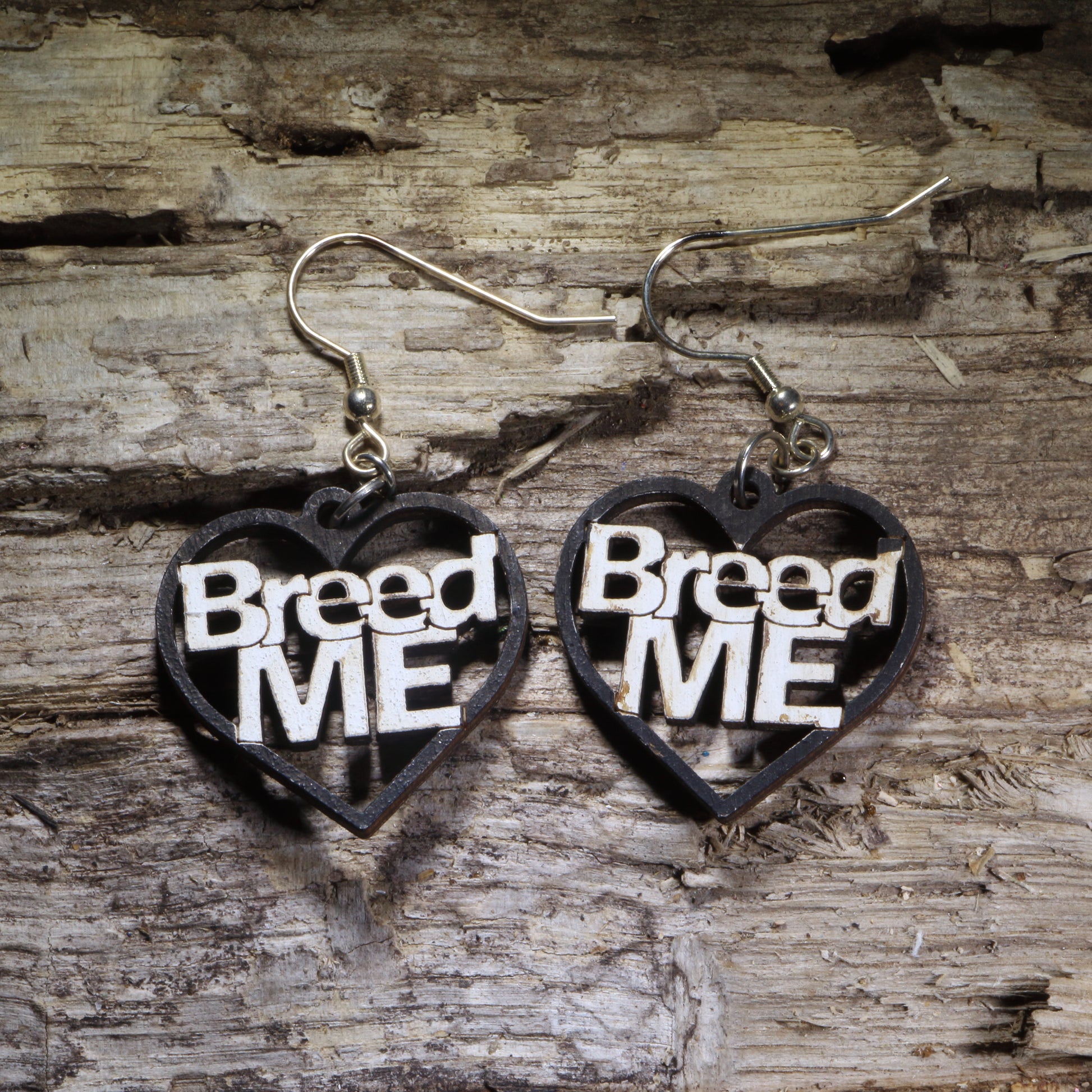 Hand-painted “Breed Me” heart wooden dangle earrings featuring bold black-and-white lettering for a cheeky adult statement. Lightweight novelty earrings perfect for risqué humor, bachelorette parties, alternative style, and funny conversation-starting jewelry.