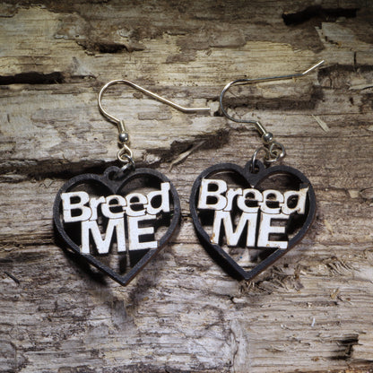 Hand-painted “Breed Me” heart wooden dangle earrings featuring bold black-and-white lettering for a cheeky adult statement. Lightweight novelty earrings perfect for risqué humor, bachelorette parties, alternative style, and funny conversation-starting jewelry.