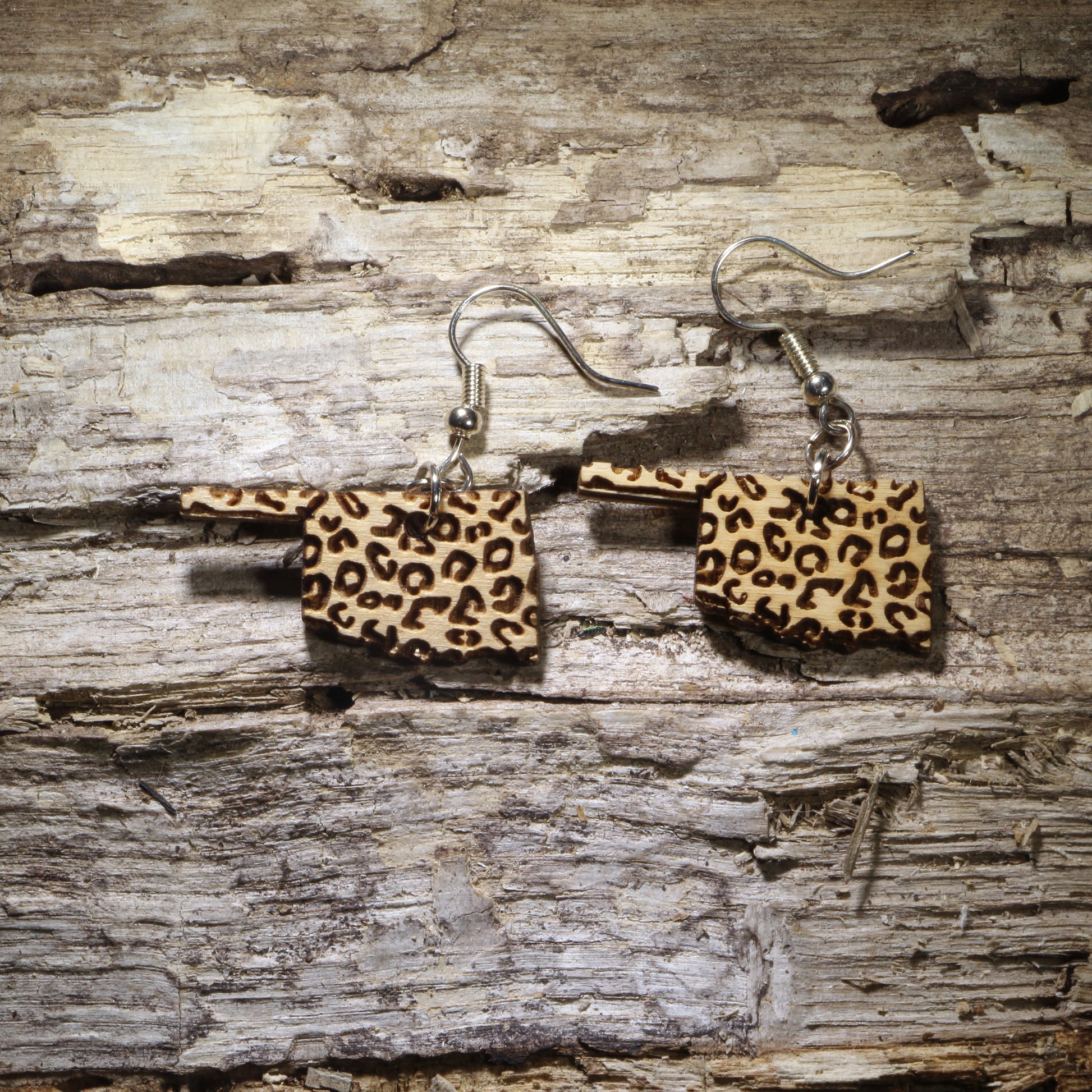 Hand-painted Oklahoma wooden dangle earrings featuring a trendy leopard print design on lightweight wood with hypoallergenic .925 sterling silver hooks. Perfect for Oklahoma lovers, animal print fans, western fashion enthusiasts, boutique style, and unique handcrafted statement jewelry.