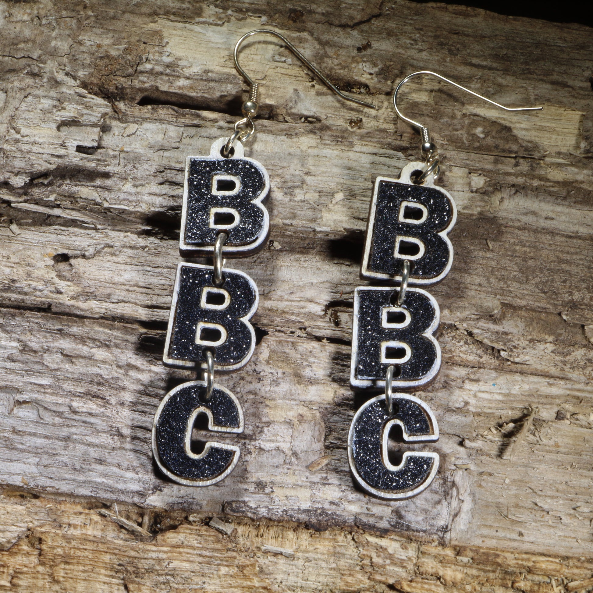Hand-painted wooden "BBC" letter dangle earrings with black glitter accents on hypoallergenic .925 sterling silver hooks. Lightweight initial letter jewelry featuring stacked B-B-C letters, perfect for personalized gifts, school spirit, team pride, or custom monogram accessories.
