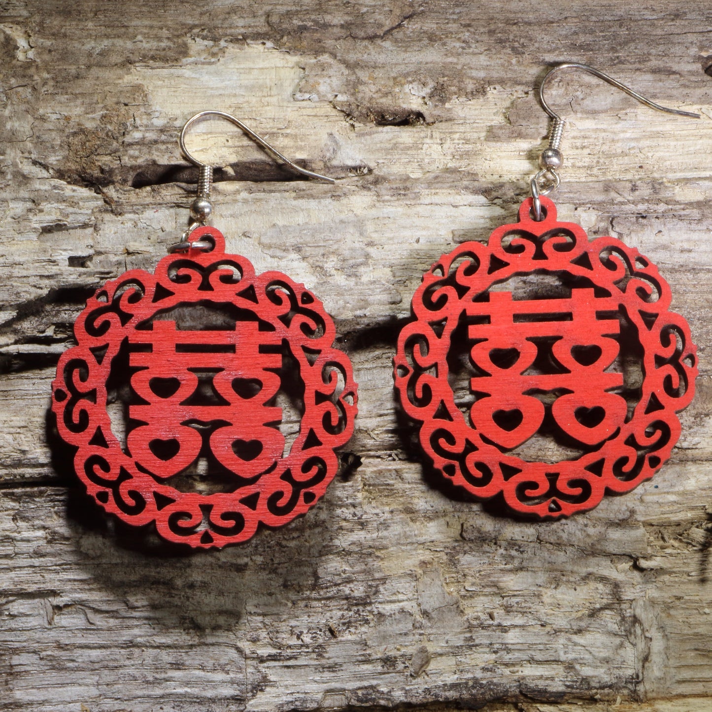 Hand-painted wooden Chinese Double Happiness symbol dangle earrings featuring an intricate circular red cutout design on hypoallergenic .925 sterling silver hooks. Lightweight Chinese wedding jewelry celebrating love, marriage, good fortune, and traditional Chinese culture.