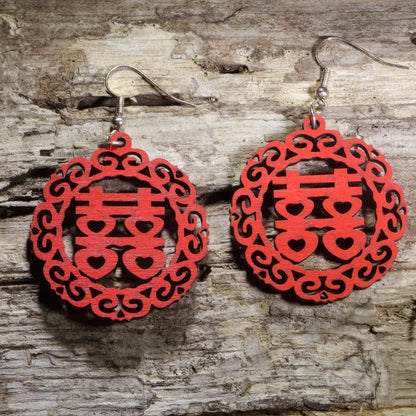 Hand-painted wooden Chinese Double Happiness symbol dangle earrings featuring an intricate circular red cutout design on hypoallergenic .925 sterling silver hooks. Lightweight Chinese wedding jewelry celebrating love, marriage, good fortune, and traditional Chinese culture.