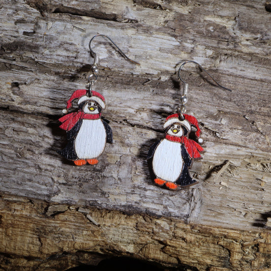 Hand-painted wooden Santa penguin dangle earrings featuring an adorable penguin dressed in a festive Santa hat. Lightweight Christmas earrings with hypoallergenic .925 sterling silver hooks, perfect for holiday parties, winter celebrations, stocking stuffers, penguin lovers, and festive seasonal outfits.