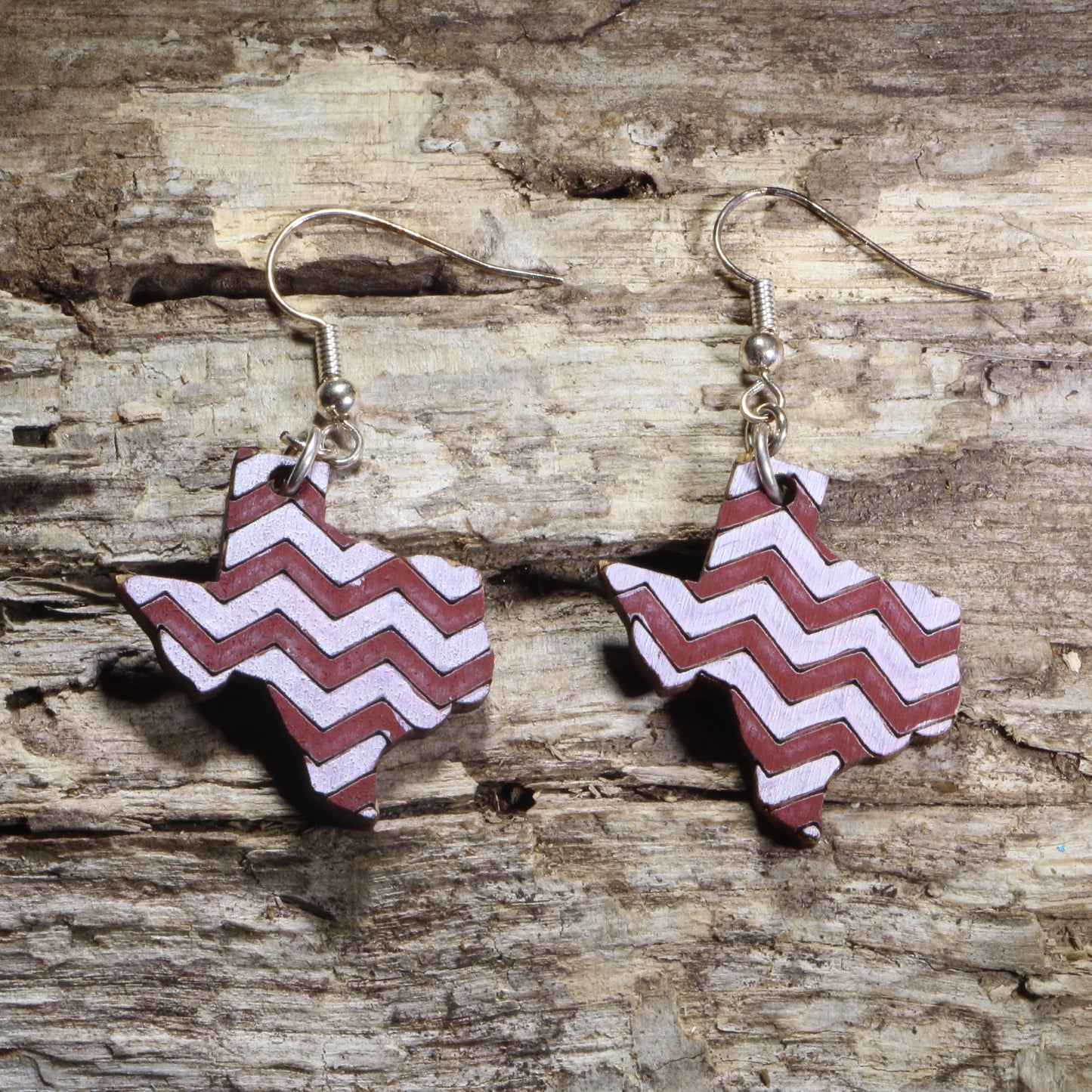 Hand-painted wooden Texas dangle earrings featuring a maroon and white chevron pattern on hypoallergenic .925 sterling silver hooks. Lightweight Texas-themed jewelry for game day, hometown pride, travel souvenirs, and unique regional accessories.