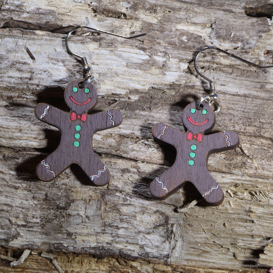 Hand-painted wooden chocolate gingerbread man dangle earrings with festive Christmas details. Lightweight holiday earrings featuring hypoallergenic .925 sterling silver hooks, perfect for Christmas parties, cookie exchanges, winter celebrations, and seasonal gift giving.