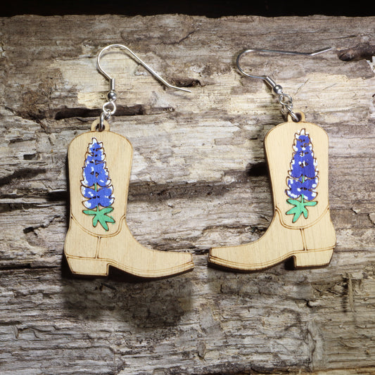 Hand-painted wooden cowboy boot dangle earrings featuring bluebonnet flowers on hypoallergenic .925 sterling silver hooks. Lightweight western floral jewelry for cowgirl style, bluebonnet lovers, rodeo outfits, country fashion, and Texas wildflower enthusiasts.