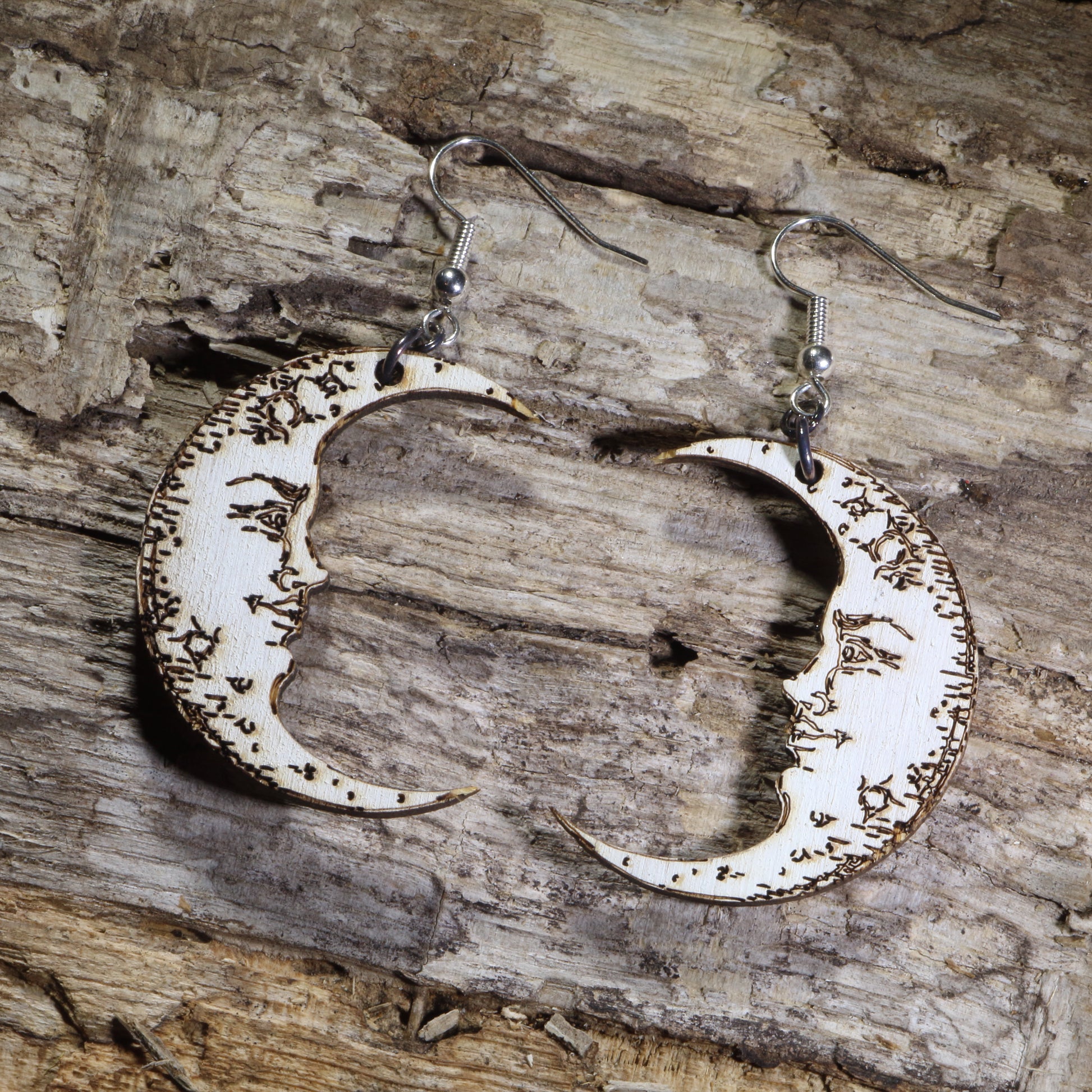 Hand-painted wooden crescent moon dangle earrings featuring engraved vintage moon face details on hypoallergenic .925 sterling silver hooks. Lightweight celestial jewelry perfect for moon lovers, astrology enthusiasts, witchy style, gothic fashion, and lunar-inspired accessories.