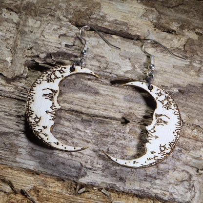 Hand-painted wooden crescent moon dangle earrings featuring engraved vintage moon face details on hypoallergenic .925 sterling silver hooks. Lightweight celestial jewelry perfect for moon lovers, astrology enthusiasts, witchy style, gothic fashion, and lunar-inspired accessories.