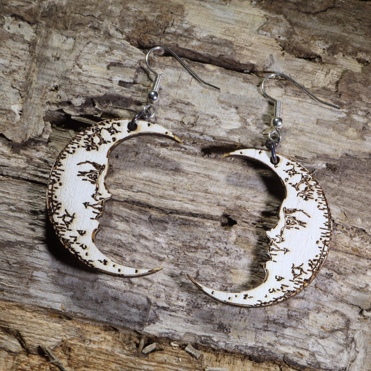 Hand-painted wooden crescent moon dangle earrings featuring engraved vintage moon face details on hypoallergenic .925 sterling silver hooks. Lightweight celestial jewelry perfect for moon lovers, astrology enthusiasts, witchy style, gothic fashion, and lunar-inspired accessories.