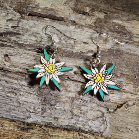 Hand-painted wooden edelweiss flower dangle earrings featuring white alpine blossoms with yellow centers and teal accents on hypoallergenic .925 sterling silver hooks. Lightweight floral jewelry perfect for nature lovers, hikers, alpine flower enthusiasts, Swiss and Austrian heritage, and botanical-inspired accessories.