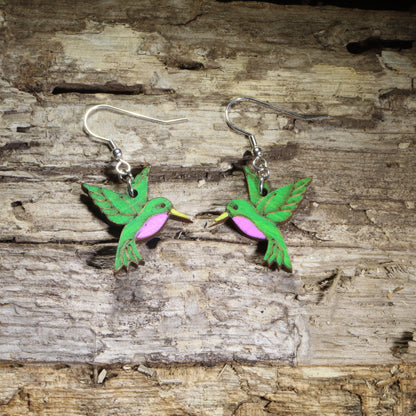 Hand-painted wooden hummingbird dangle earrings featuring vibrant green feathers, purple chest accents, and yellow beaks on hypoallergenic .925 sterling silver hooks. Lightweight bird-inspired jewelry for hummingbird lovers, bird watchers, gardeners, nature enthusiasts, and wildlife gifts.