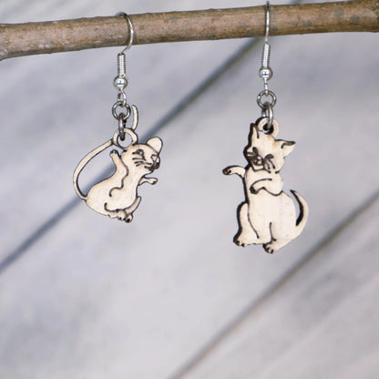 Hand-painted wooden mismatched cat and mouse dangle earrings featuring a playful white cat reaching toward a smiling mouse on hypoallergenic .925 sterling silver hooks. Lightweight animal jewelry displayed hanging from a branch for cat lovers, mouse enthusiasts, pet owners, and fans of whimsical accessories.