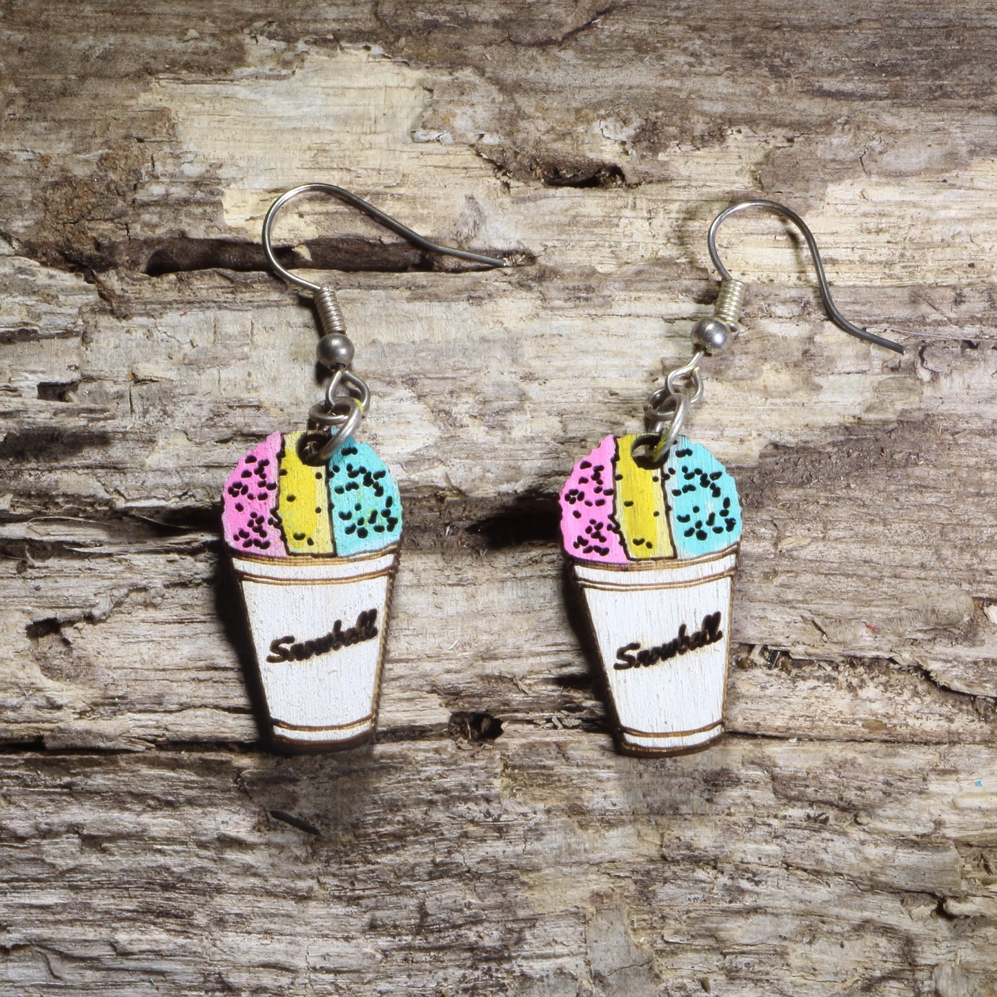 Hand-painted wooden snow cone dangle earrings featuring a white paper cup filled with pink, yellow, and blue shaved ice on hypoallergenic .925 sterling silver hooks. Lightweight summer dessert jewelry for fair lovers, carnival fans, foodies, and colorful accessory enthusiasts.