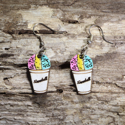 Hand-painted wooden snow cone dangle earrings featuring a white paper cup filled with pink, yellow, and blue shaved ice on hypoallergenic .925 sterling silver hooks. Lightweight summer dessert jewelry for fair lovers, carnival fans, foodies, and colorful accessory enthusiasts.