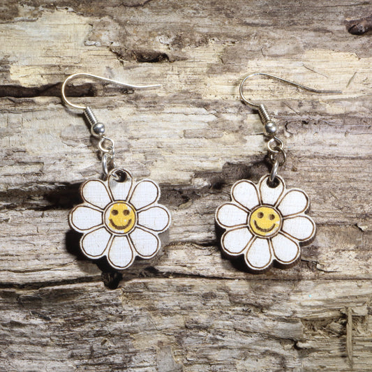Handcrafted Smiley Daisy wooden dangle earrings featuring cheerful smiling daisy flowers with bright, playful details. Lightweight laser-cut wooden earrings with hypoallergenic .925 sterling silver hooks, perfect for flower lovers, retro 70s fashion, happy aesthetic, spring accessories, cottagecore style, and fun everyday jewelry.