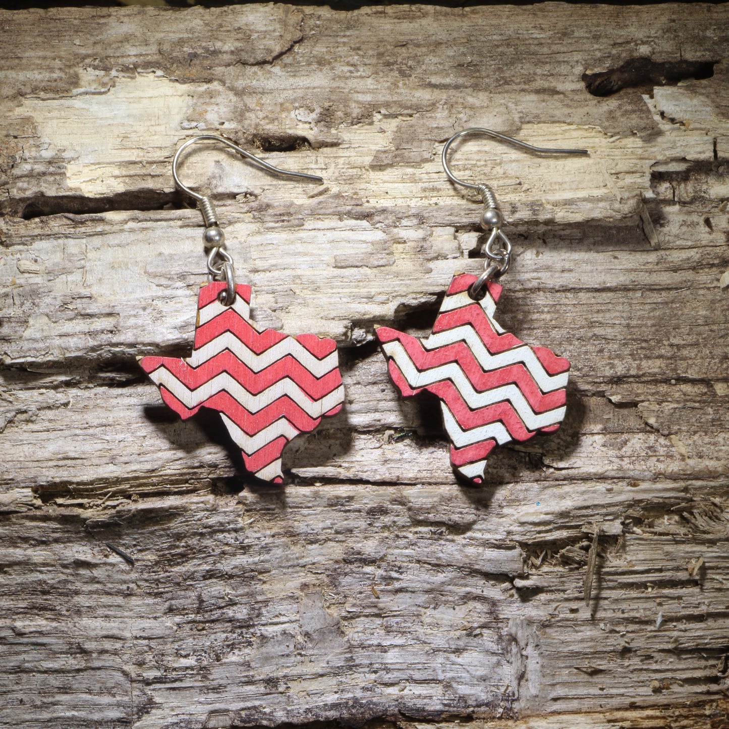 Handcrafted Texas-shaped wooden dangle earrings featuring a bold red and white chevron pattern. Lightweight Texas state earrings with hypoallergenic .925 sterling silver hooks, perfect for Texas pride, southern style, western fashion, rodeo outfits, and unique handmade statement jewelry.