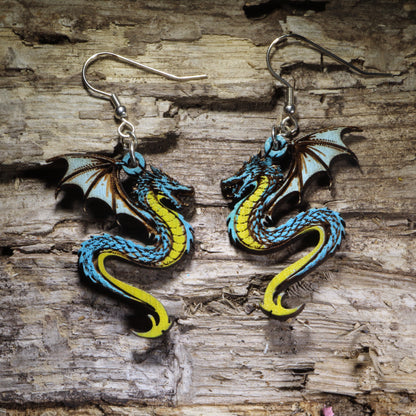 Handcrafted blue dragon wooden dangle earrings featuring a detailed hand-painted fantasy dragon with blue scales, yellow underbelly, and outstretched wings. Lightweightfeaturing a detailed hand-painted fantasy dragon with blue scales, yellow underbelly, and outstretched wings. Lightweight laser-cut wooden earrings with hypoallergenic .925 sterling silver hooks, perfect for dragon lovers, fantasy fans, Dungeons & Dragons players, Renaissance fairs, mythical creature enthusiasts, and handmade fantasy jewelry.