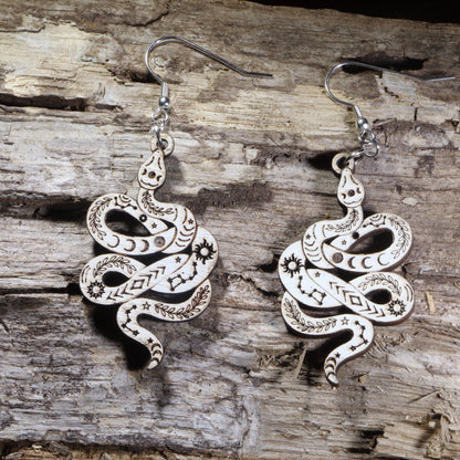 Handcrafted celestial snake wooden dangle earrings featuring engraved moon phases, stars, constellations, and botanical details. Lightweight wooden serpent earrings with hypoallergenic .925 sterling silver hooks, perfect for witchy jewelry lovers, celestial fashion, gothic style, and nature-inspired accessories.