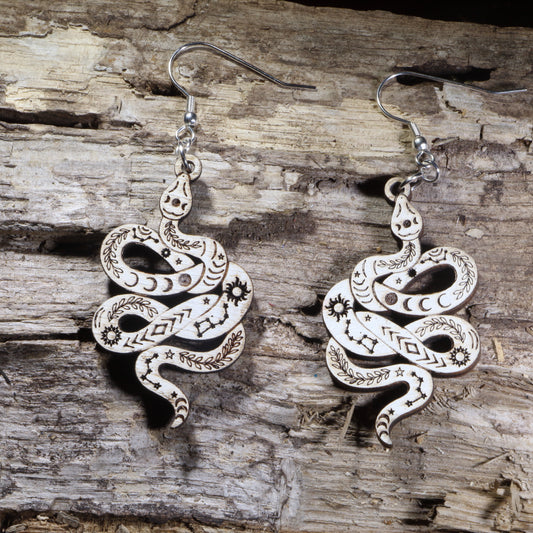 Handcrafted celestial snake wooden dangle earrings featuring engraved moon phases, stars, constellations, and botanical details. Lightweight wooden serpent earrings with hypoallergenic .925 sterling silver hooks, perfect for witchy jewelry lovers, celestial fashion, gothic style, and nature-inspired accessories.