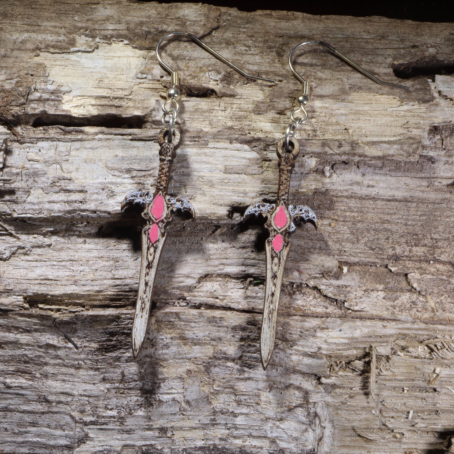 Handcrafted fantasy sword wooden dangle earrings featuring an ornate medieval blade with pink gemstone accents and detailed crossguard. Lightweight laser-cut wooden earrings with hypoallergenic .925 sterling silver hooks, perfect for fantasy fans, RPG gamers, cosplay, medieval enthusiasts, Renaissance festival outfits, and sword collectors.