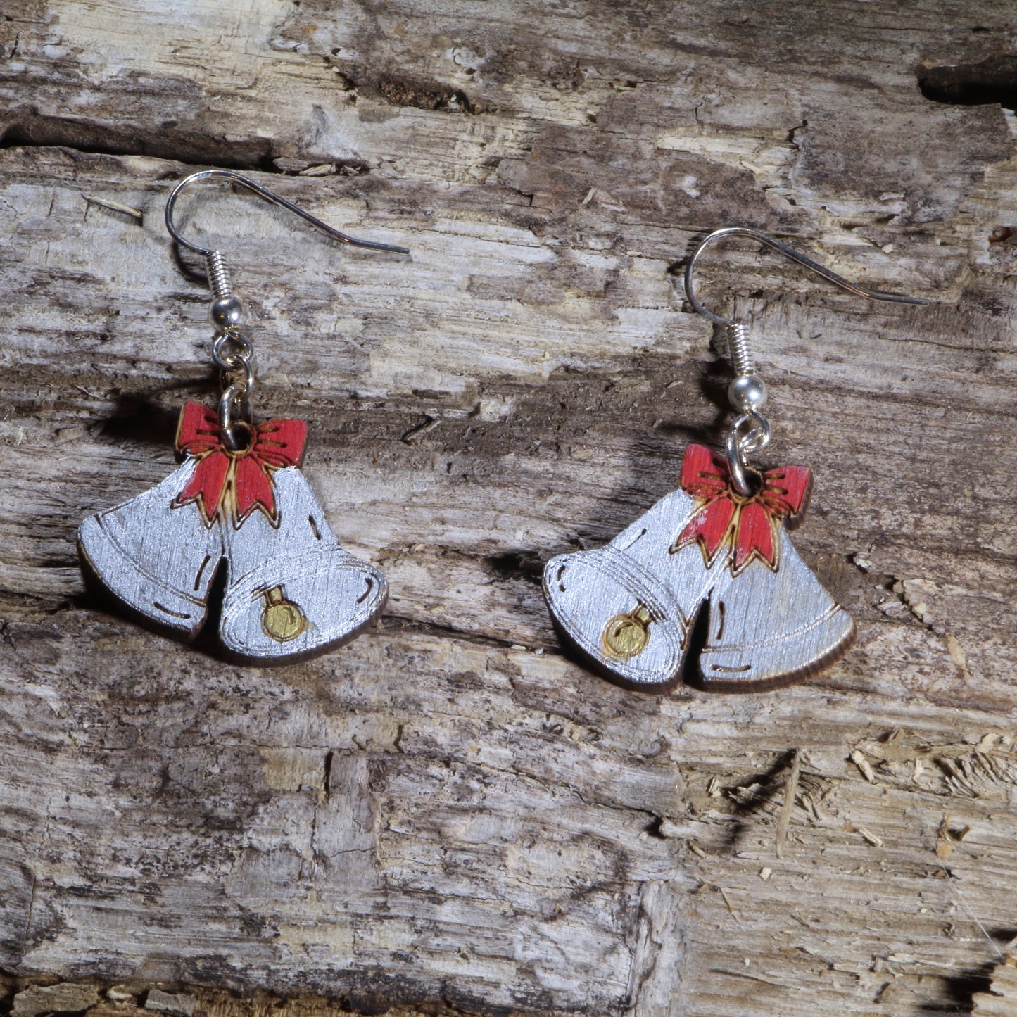 Handcrafted wooden Christmas bell dangle earrings featuring silver holiday bells accented with festive red bows and golden clappers. These lightweight Christmas earrings are finished with hypoallergenic .925 sterling silver hooks, making them a cheerful accessory for holiday parties, Christmas celebrations, winter outfits, and seasonal gift giving.