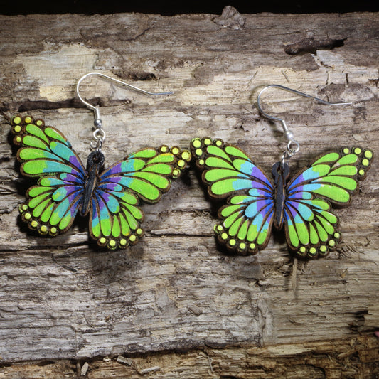 Handmade green and purple butterfly wooden dangle earrings featuring vibrant hand-painted butterfly wings with detailed laser-cut accents. Lightweight butterfly earrings crafted from wood with hypoallergenic .925 sterling silver hooks, perfect for butterfly lovers, nature enthusiasts, gardeners, insect fans, and colorful wildlife jewelry collectors.