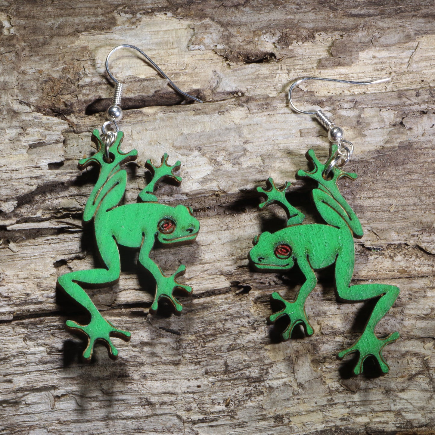 Handmade green tree frog wooden dangle earrings featuring detailed laser-cut frogs with bright green painted finish and red eyes. Lightweight frog earrings crafted from wood with hypoallergenic .925 sterling silver hooks, perfect for amphibian lovers, nature enthusiasts, wildlife fans, rainforest lovers, and unique animal jewelry collectors.