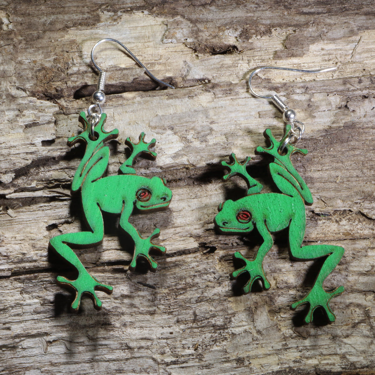 Handmade green tree frog wooden dangle earrings featuring detailed laser-cut frogs with bright green painted finish and red eyes. Lightweight frog earrings crafted from wood with hypoallergenic .925 sterling silver hooks, perfect for amphibian lovers, nature enthusiasts, wildlife fans, rainforest lovers, and unique animal jewelry collectors.