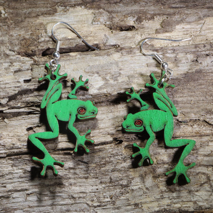 Handmade green tree frog wooden dangle earrings featuring detailed laser-cut frogs with bright green painted finish and red eyes. Lightweight frog earrings crafted from wood with hypoallergenic .925 sterling silver hooks, perfect for amphibian lovers, nature enthusiasts, wildlife fans, rainforest lovers, and unique animal jewelry collectors.