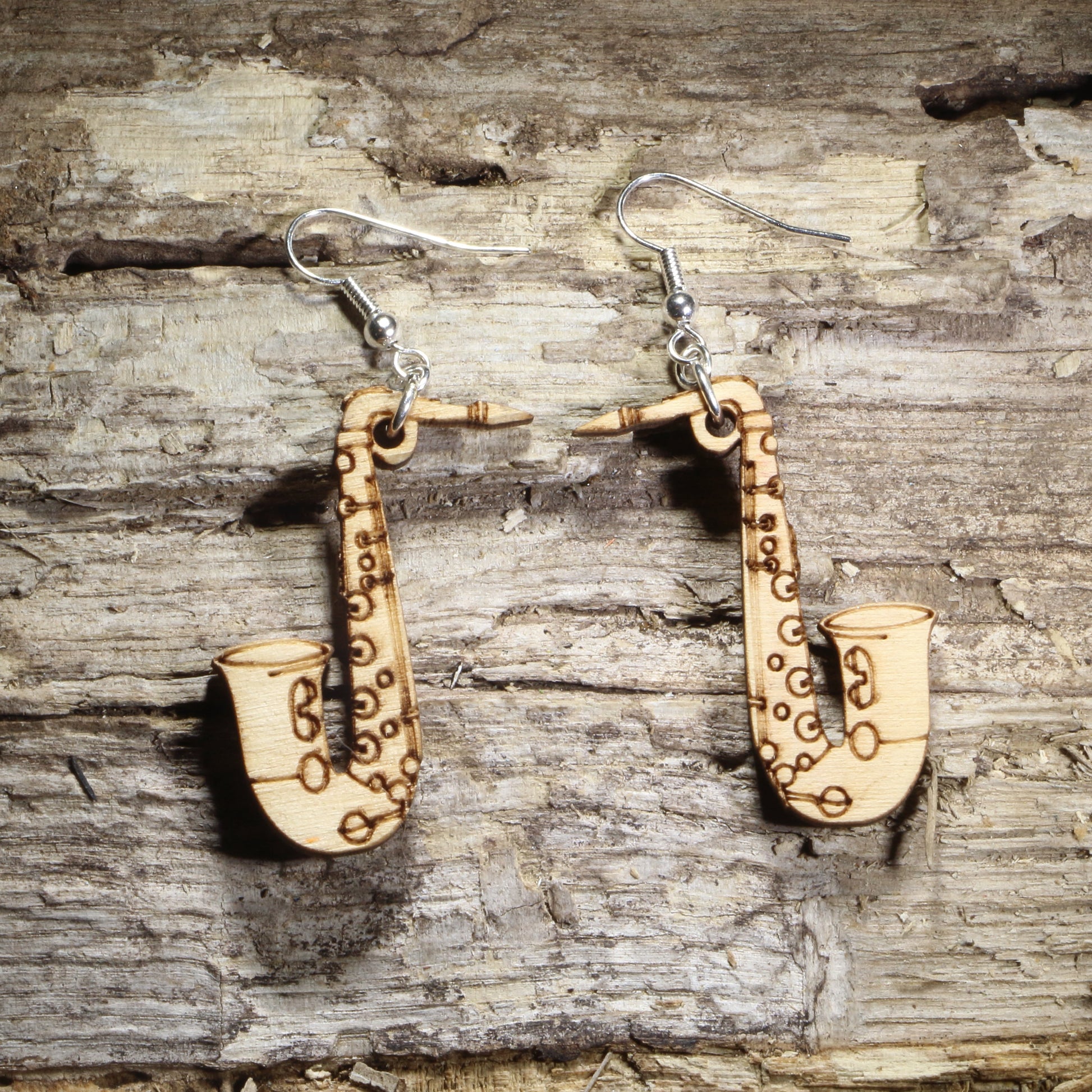 Handmade natural wood saxophone dangle earrings crafted from lightweight laser-cut wood with hypoallergenic .925 sterling silver hooks. Music-themed jewelry perfect for saxophone players, jazz musicians, band members, orchestra performers, and music teachers.