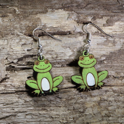 Handmade smiling frog wooden dangle earrings featuring adorable green frogs with white bellies and cheerful expressions. Lightweight frog earrings crafted from wood with hypoallergenic .925 sterling silver hooks, perfect for frog lovers, amphibian enthusiasts, nature lovers, pond wildlife fans, and whimsical animal jewelry collectors.