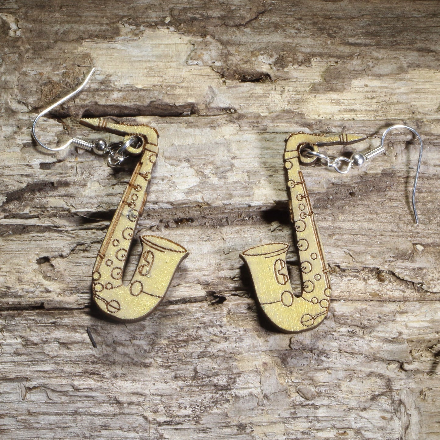 Handmade wood gold saxophone dangle earrings showing the laser-cut wooden design and hypoallergenic .925 sterling silver hooks. Lightweight musical instrument earrings for saxophonists, jazz lovers, concert band musicians, and music educators.