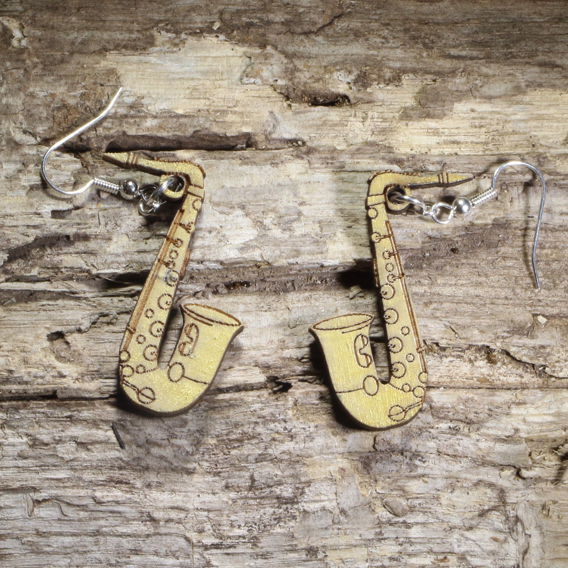 Handmade wood gold saxophone dangle earrings showing the laser-cut wooden design and hypoallergenic .925 sterling silver hooks. Lightweight musical instrument earrings for saxophonists, jazz lovers, concert band musicians, and music educators.