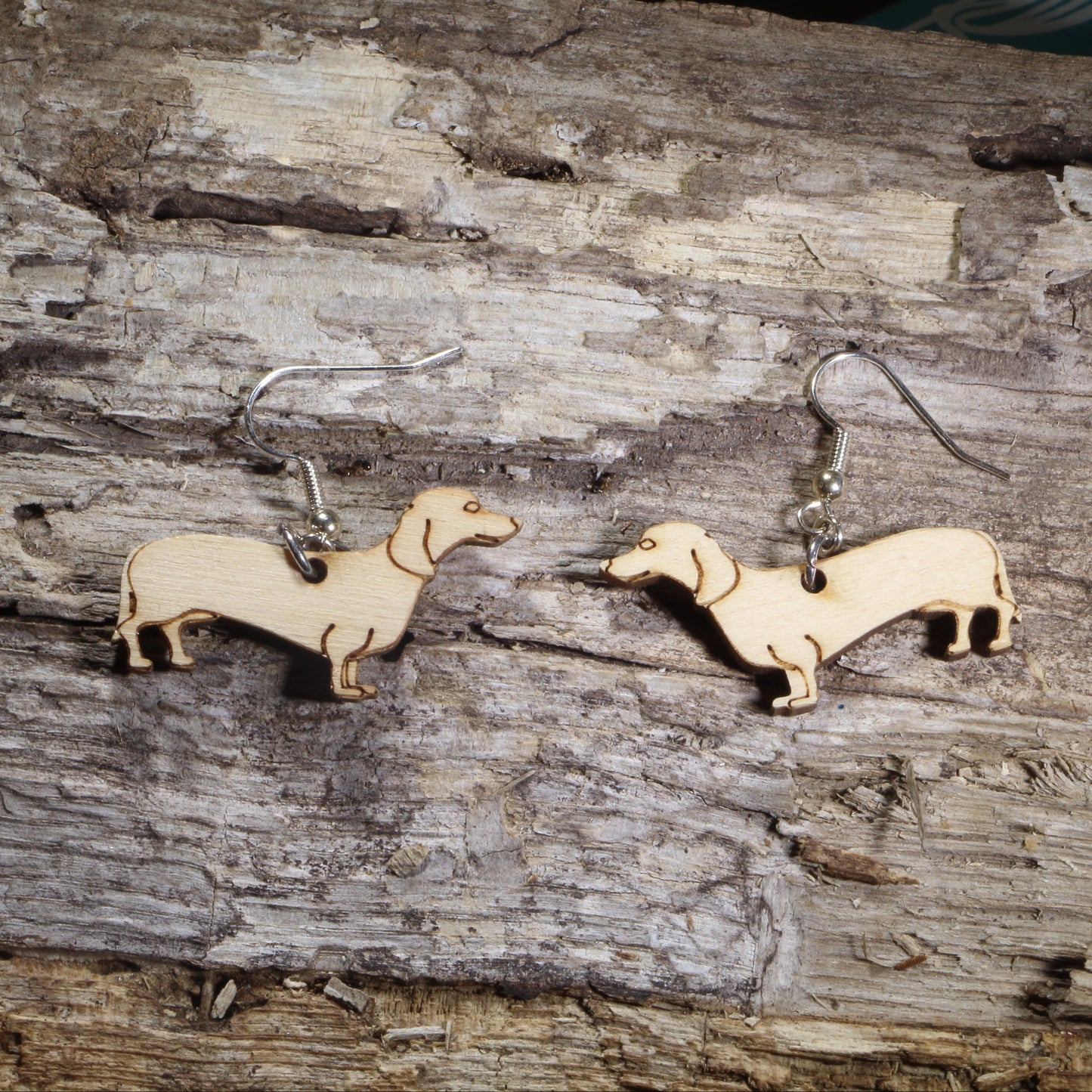 Handmade wooden Dachshund dangle earrings with engraved details, shown on hypoallergenic .925 sterling silver hooks. Lightweight dog lover earrings featuring adorable wiener dog silhouettes, perfect for Dachshund owners, pet lovers, and unique animal jewelry fans.