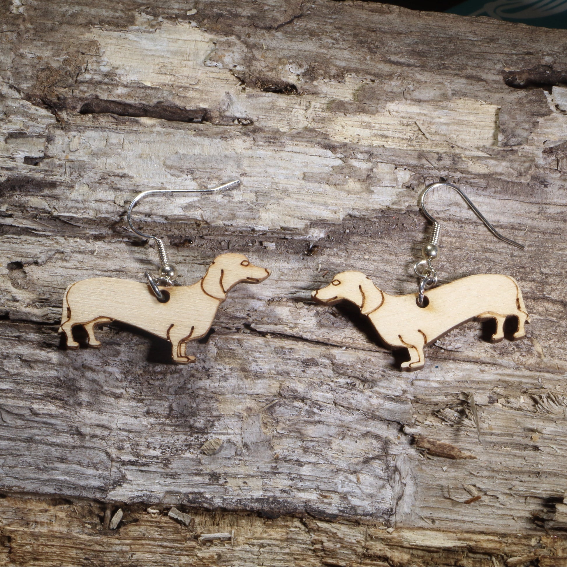 Handmade wooden Dachshund dangle earrings with engraved details, shown on hypoallergenic .925 sterling silver hooks. Lightweight dog lover earrings featuring adorable wiener dog silhouettes, perfect for Dachshund owners, pet lovers, and unique animal jewelry fans.